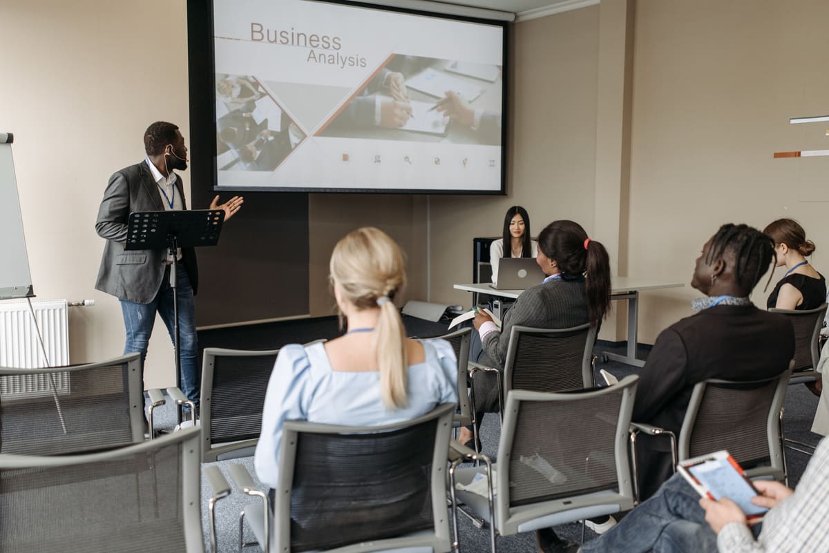 A trainer presenting a business analysis session to a seated cohort