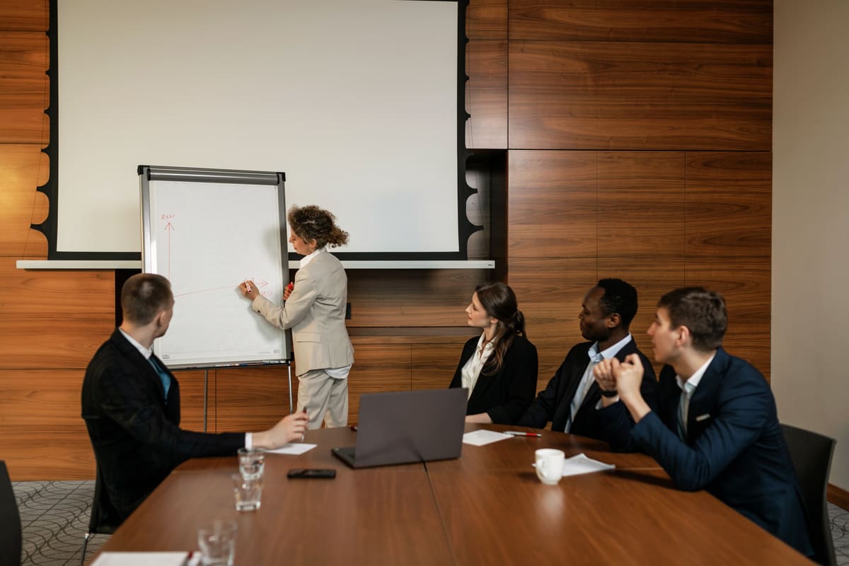 A consultant sketching a growth trend on a whiteboard for the team